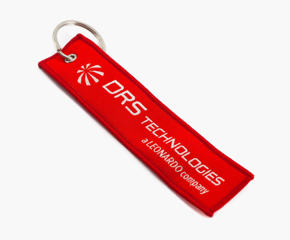 Custom remove before flight tag keyrings with white letters on a red background (Pantone matched).