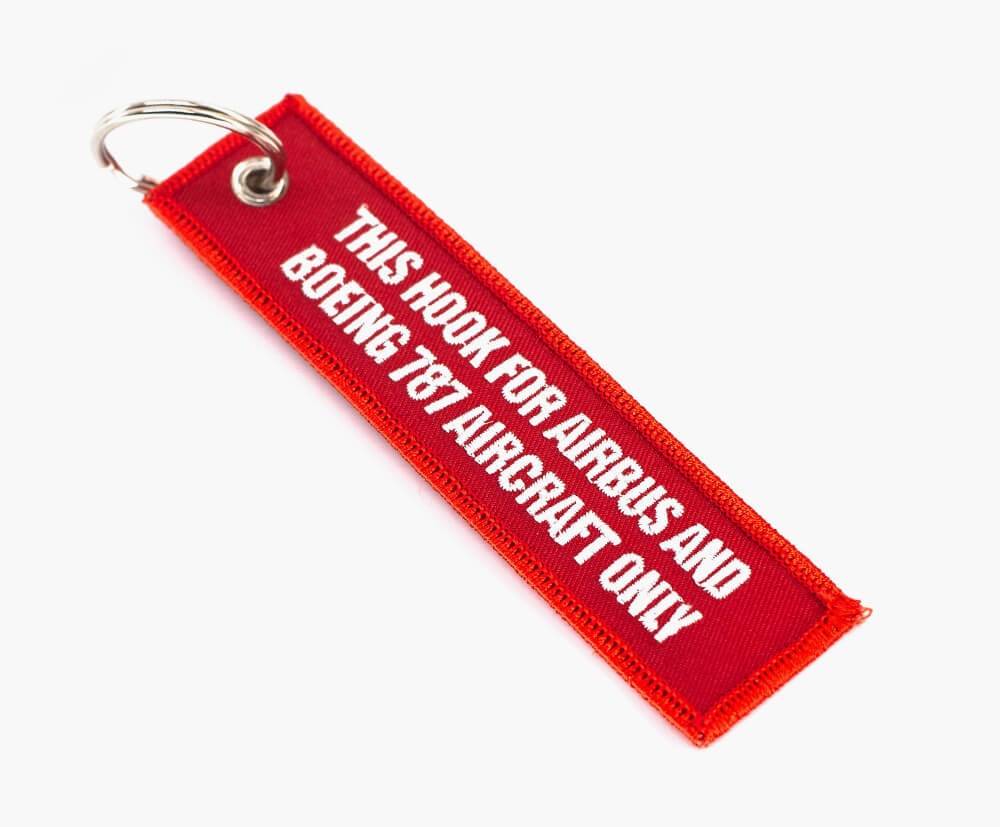 Bold text embroidered in white on the remove before flight keyrings.
