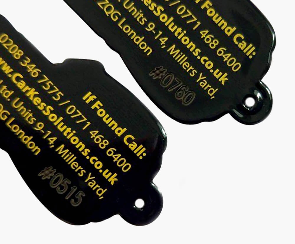 Sequential or variable data engraved onto the reverse of black custom shaped rubber style keyrings.